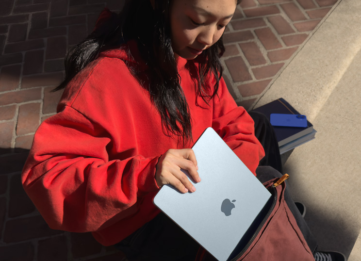 石段に座り、MacBookをバックパックに入れている人物